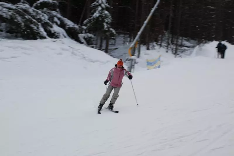 Skifahrerin in rosa Skijacke auf einer verschneiten Piste