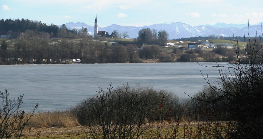 Vereister Soyensee mit Kirche und den Chiemgauer Alpen im Hintergrund; die Kampenwand ist ganz links zu sehen.