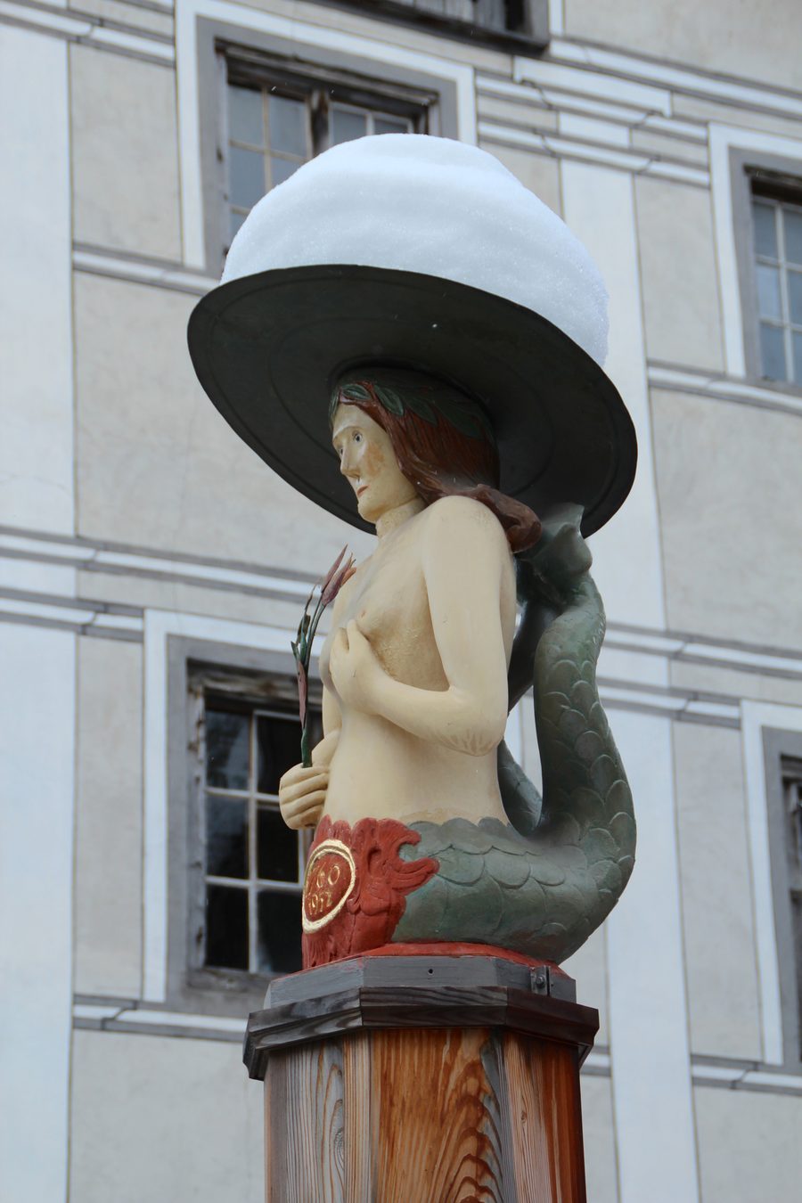 Brunnenfigur des historischen Holzbrunnens in Valendas mit Schneehut
