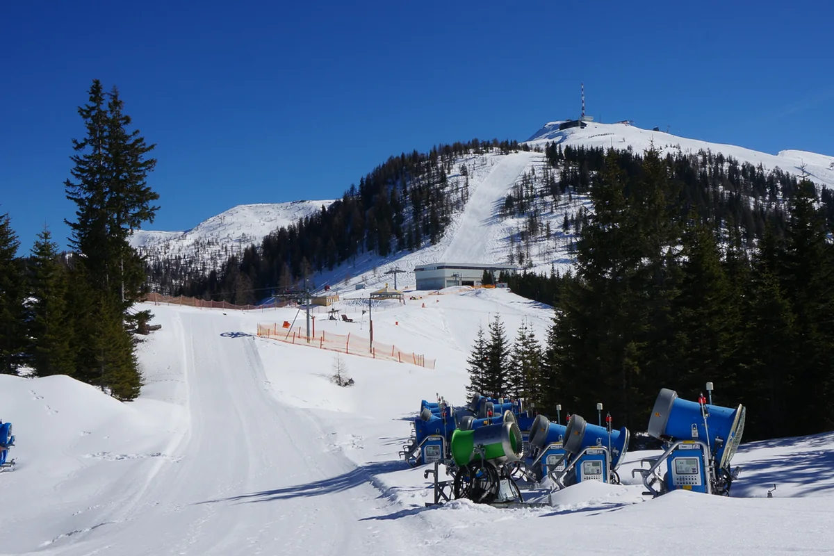 Verschneite Piste und Beschneiungsanlagen im Skizentrum Goldeck in Kärnten.