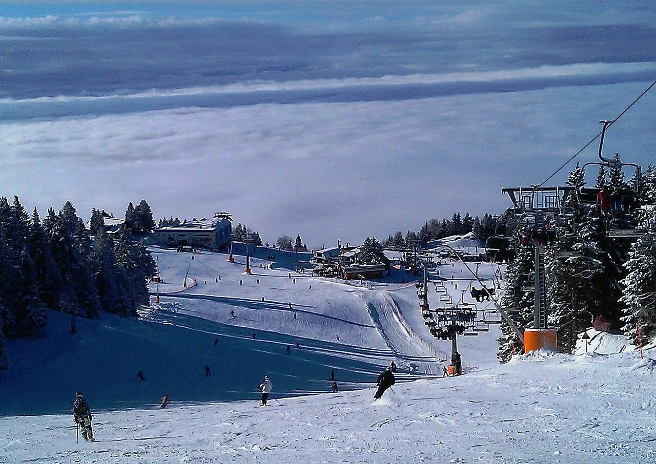 Skifahrer und Sessellift auf den verschneiten Pisten des Skigebiets Krvavec in Slowenien.
