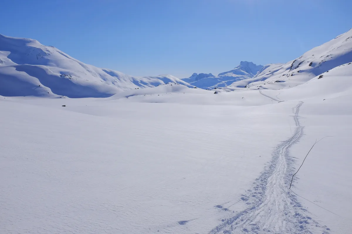 Verschneite Berglandschaft mit einer Skispur im Storutladalen im Jotunheimen-Nationalpark in Norwegen.