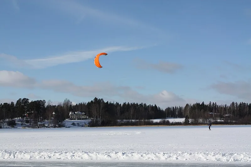 Kiteskifahrer mit Zugdrachen auf einer verschneiten Fläche