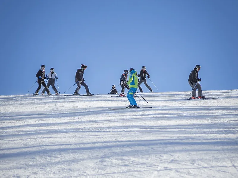 Skilehrer gibt einer Gruppe auf der verschneiten Piste Anweisungen